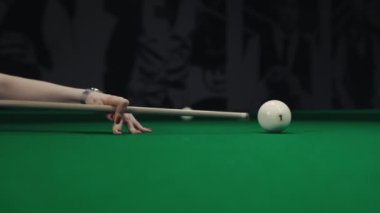 Kadın bilardo oynuyor, adam bilardo topunu vurmayı hedefliyor..