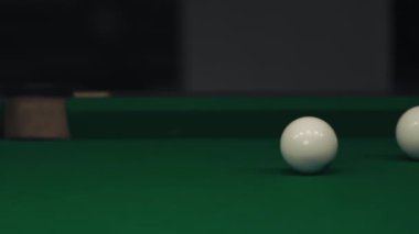 Karanlık bir odada yeşil bir masada bilardo oynamak. Erkek ya da kadın toplara ıstakayla vuruyor ve deliğe vuruyor.