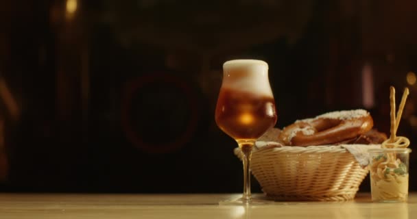 一杯啤酒 配上椒盐卷饼和小点心 放在木制桌子上 啤酒是泡沫的 — 图库视频影像