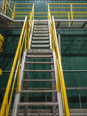 Endüstriyel iç döşeme, metalik renkli merdiven ve sarı parmaklıklar.