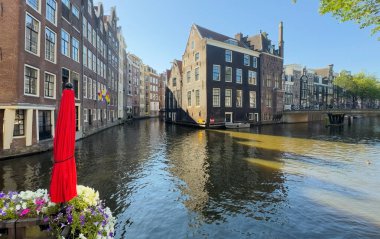 Amsterdam şehir manzarası, kanallar, eski evler ve tekneler. Yazın gün batımında Amsterdam 'ın güzel manzarası. Avrupa 'nın ünlü şehrine seyahat Amsterdam, Hollanda, Hollanda