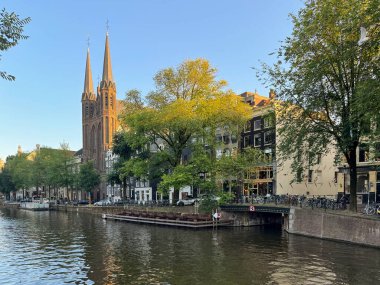 Amsterdam şehri, Singel kanalı, eski evler ve De Krijtberg kilisesi. Yazın gün batımında Amsterdam 'ın güzel manzarası. Avrupa 'nın ünlü şehrine seyahat Amsterdam, Hollanda, Hollanda