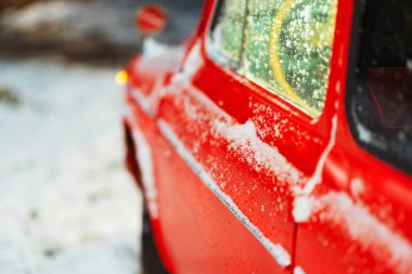Sokakta kırmızı bir arabanın arkasında Noel karı var. Fotoğraf stüdyosunda gerçek bir araba olan yeni yıl fotoğraf bölgesi. Kırmızı boyayla boyanmış eski bir arabanın üzerindeki beyaz kar.
