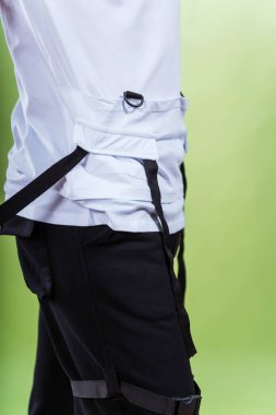 Yeşil arka plandaki beyaz tişörtün ayrıntıları. Sade renkli bir arka planda bir yaz tişörtünün makro fotoğrafı. Bir fotoğraf stüdyosunda yaz kıyafetlerinin fotoğraf çekimi.