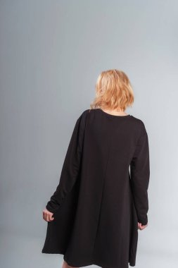 Beyaz arka planda siyah elbiseli bir kızın arkası. Kız geri döndü.