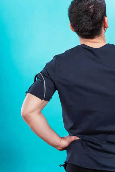 guy in a black t-shirt on a blue background. the back of a man in a black T-shirt on a plain colored background. photo session of summer clothes in a photo studio