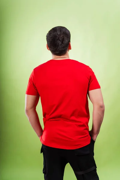 stock image guy in a red t-shirt on a green background. the back of a man in a white T-shirt on a plain colored background. photo session of summer clothes in a photo studio