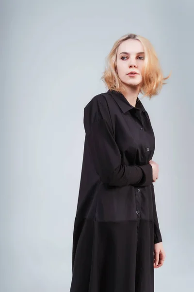 stock image portrait of a Russian girl in a black dress on a white background. photo session of black clothes on a light background. blonde girl in black cotton dress