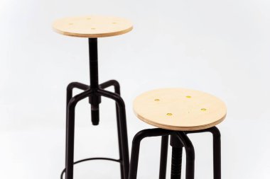 Beyaz arka planda ahşap yuvarlak koltuklu siyah demir sandalye. Kaynağı siyah borulardan yapılmış, arka planda dönen bir koltuğu var.