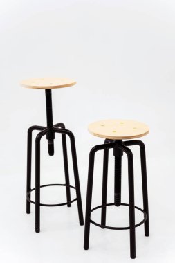 Beyaz arka planda ahşap yuvarlak koltuklu siyah demir sandalye. Kaynağı siyah borulardan yapılmış, arka planda dönen bir koltuğu var.