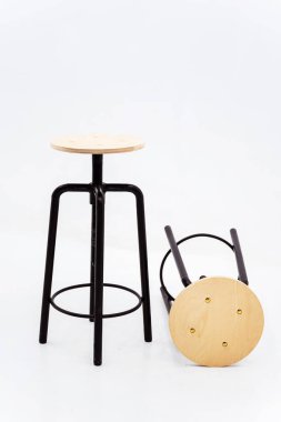 Beyaz arka planda ahşap yuvarlak koltuklu siyah demir sandalye. Kaynağı siyah borulardan yapılmış, arka planda dönen bir koltuğu var.