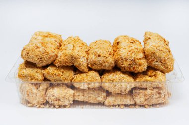 Beyaz arka planda serpiştirilmiş küçük tatlı kekler. Napolyon keki arka planda parçalara ayrılmış. Kırıntılar serpiştirilmiş küçük kekler.