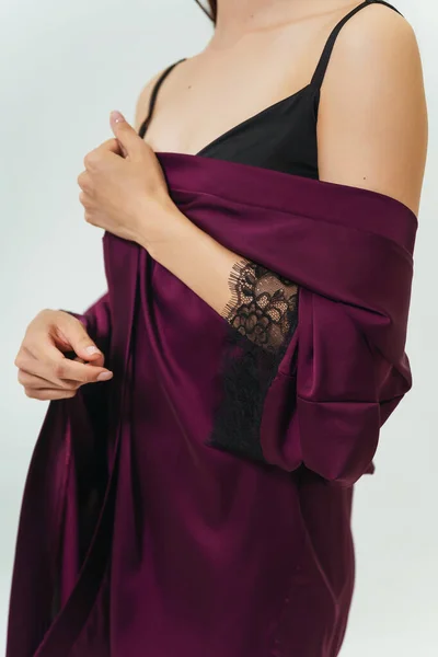 details of a purple and black nightgown on a girl. photo session of a silk women\'s sleep set on a woman.