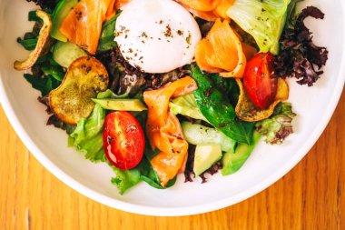 Taze sebzeli salata ve kafeterya masasında balık parçaları. Yaz restoranında avokado ve somon dilimli hafif salata.