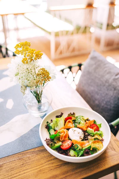 Taze sebzeli salata ve kafeterya masasında balık parçaları. Yaz restoranında avokado ve somon dilimli hafif salata.