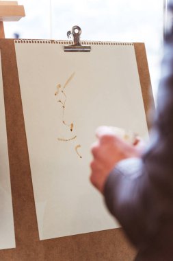 Bir adam beyaz bir kağıt parçasına kahve içeceği çizer. İstanbul kahve fuarında eğlence. Sergi konukları için kahve telvesi hazırlıyorum.