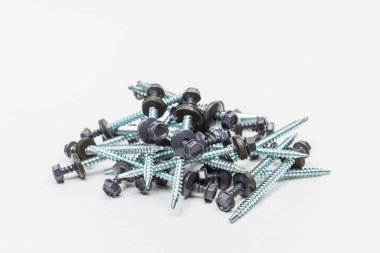 Beyaz arka planda çatı vidaları. Katalog için arka planda kendi kendine dokunan vidaların fotoğrafı. Metal kiremitler ve demirle çalışmak için cıvatalar.