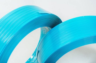 Beyaz arka planda mavi polyester bant. Arka planda hafif bir rulo halinde yüksek güçlü temoplastik bant. rulo içinde bant paketleme materyali