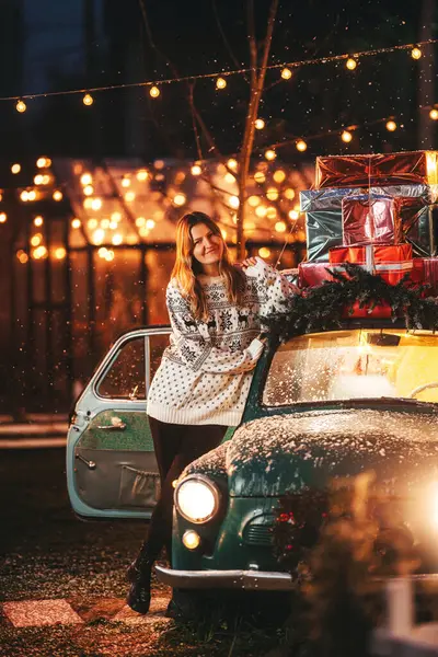 photo shoot of a girl in a warm hoodie on Christmas day. photo of a woman in a New Year's sweater at a Christmas car. photo shoot of a person on New Year's decorations in a photo studio in Kazakhstan