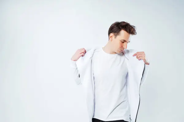 a photo shoot of a Russian guy on a white background. The Russian model poses in a fashionable warm hoodie. photo shoot of youth clothes with a model in a photo studio