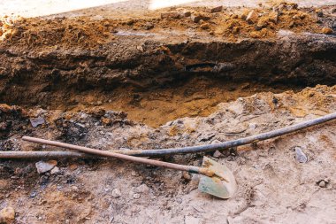 Boru döşemek için yükleyicisi olan açık bir çukur. Şehirdeki iletişimi geliştirmek için asfalt bir yol. İnşaat işleri için siperlerin hazırlanması