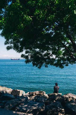 İstanbul 'da bir rıhtımda oturan yalnız bir adam. Siyah kapüşonlu bir adam deniz kenarındaki kayalarda oturuyor.