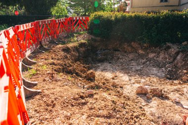 Boru döşemek için yükleyicisi olan açık bir çukur. Şehirdeki iletişimi geliştirmek için asfalt bir yol. İnşaat işleri için siperlerin hazırlanması