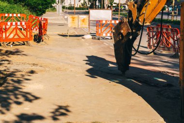 Asfaltı kırmak için bir yükleyicinin matkabı. İletişim kurmak için yolun sökülmesi. Eski şehir ağlarının onarımı