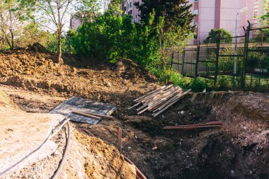 Boru döşemek için yükleyicisi olan açık bir çukur. Şehirdeki iletişimi geliştirmek için asfalt bir yol. İnşaat işleri için siperlerin hazırlanması