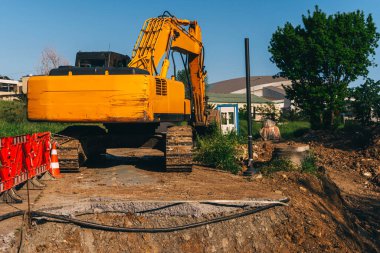 Boru döşemek için yükleyicisi olan açık bir çukur. Şehirdeki iletişimi geliştirmek için asfalt bir yol. İnşaat işleri için siperlerin hazırlanması