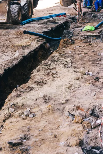 Boru döşemek için yükleyicisi olan açık bir çukur. Şehirdeki iletişimi geliştirmek için asfalt bir yol. İnşaat işleri için siperlerin hazırlanması