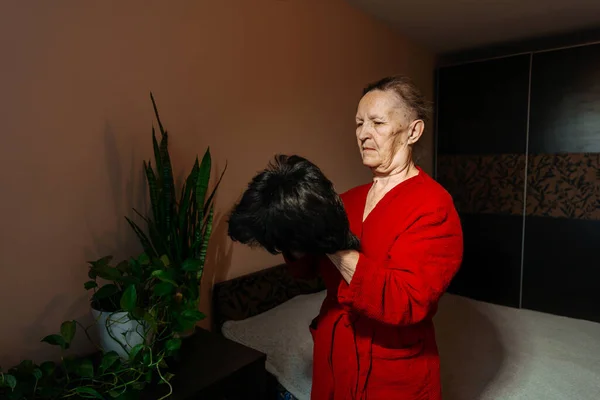 balding grandmother from chemotherapy with a hat. hair loss in a woman due to a cancerous tumor. an artificial wig on my grandmother\'s head because of cancer