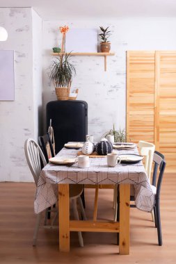 Mutfağın arka planında siyah buzdolabı olan ahşap bir mutfak masası. Fotoğraf stüdyosunda mutfak dekorasyonu. Fotoğraf çekimleri için mutfak masasında aletler ve tabaklar var.