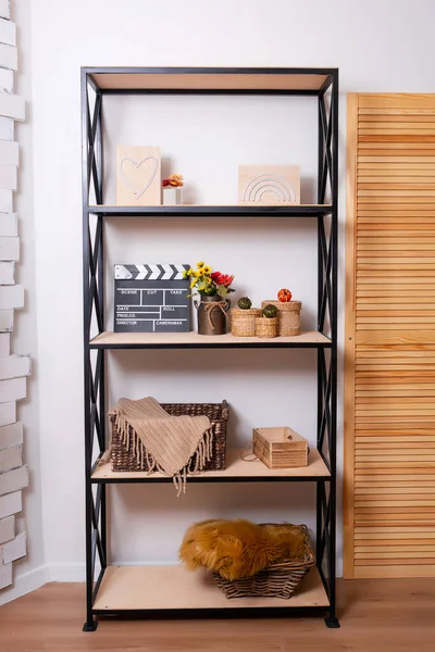 black iron shelving with wooden shelves and decor for a photo shoot. shelves with different things in the room. an open cabinet with objects in the photo studio
