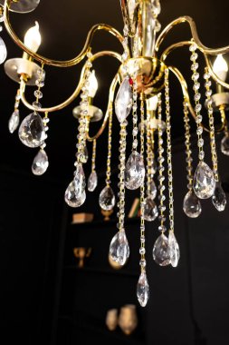 Siyah duvarda kristal bir avize. Siyah bir odada yaldızlı camlı bir avize. Fotoğraf stüdyosunda gotik stil.