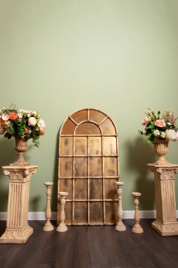 Altın aynalı demir bir çerçeve ve kaidede saksılar. Fotoğraf stüdyosunda çiçekli, sütunlu ve aynalı bir fotoğraf bölgesi. düğün fotoğrafı bölgesi