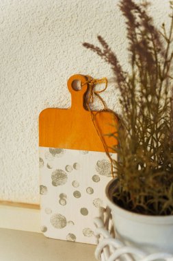 Mutfak tezgahında canlı bir saksı bitkisinin yanına güzel bir tahta kesme tahtası yerleştiriliyor. Dekoru yükseltiyor.