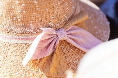 Detaylı bir yakın çekim görüntüsü, aksesuara büyüleyici bir yetenek katan güzel pembe bir fiyonkla süslenmiş şık bir şapka sergiliyor.