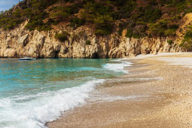 Güzel bir tekne, sakin sularda nazikçe yüzüyor. Tam kumlu bir sahilin yanında, manzaralı bir manzara sunuyor.