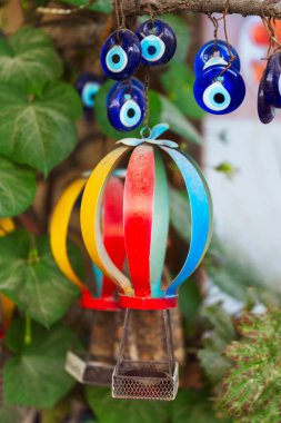 Zararlı şeytani gözleri olan parlak ve renkli bir sıcak hava balonu herkesin görebileceği bir ağaç dalından nazikçe sarkıtılır.