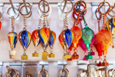 Renkli sıcak hava balonlarının canlı bir çeşidi sanatsal olarak sergilenmiş, güçlü bir direğe nazikçe asılmış, neşeli bir ortam yaratıyor.