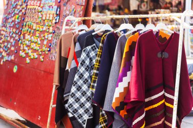 Renkli kıyafetlerin canlı bir çeşidi zarif bir şekilde sallanıyor, çeşitli stiller ve renkler sergiliyor.