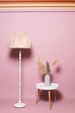 Pembe arka planda plastik beyaz masa olan uzun boylu bir lamba. Mobilyaların rengi farklı. Yüksek kalite fotoğraf