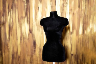 Altın duvara karşı yumuşak siyah manken. Kadın soyunma odası mankeni siyah kumaşla kaplı. Yüksek kalite fotoğraf