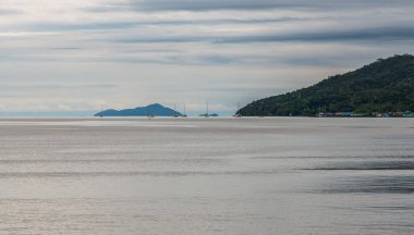 Nefes kesici ve huzurlu bir kıyı manzarası. Resmedilmeye değer bir ada ve sakin suların üzerindeki dramatik bulutlar.