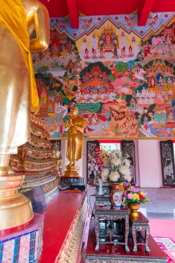 Huzurlu iç mekanda heybetli bir Buda heykeli ve rahatlatıcı bir tapınak atmosferinde renkli resimler var.