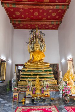 Huzurlu iç mekanda heybetli bir Buda heykeli ve rahatlatıcı bir tapınak atmosferinde renkli resimler var.