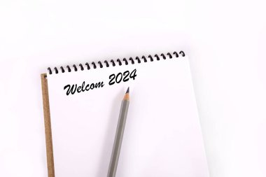 Text 2024 on a white background. New year 2024. Notepad and pencil on a white background. Business diary cover for 2024. planning concept 2024