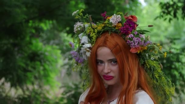 美丽的女孩穿着绣花民族服装 红头发 头戴花冠 站在树旁 童话人物 森林精神 Mavka 4K分辨率 — 图库视频影像