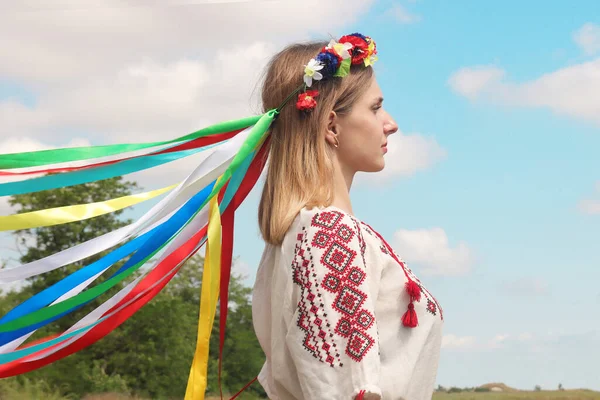 ポートレートのウクライナの若いです女の子でプロフィールで国家衣装とともに花輪で彼女の頭の上に青空の背景 — ストック写真